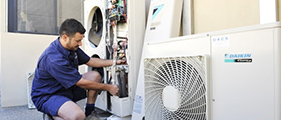 Southern Comfort technician in work uniform servicing a Daikin outdoor heat pump unit