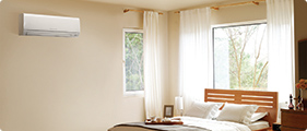 Bedroom with a wall-mounted heat pump unit above the window keeping the room comfortable